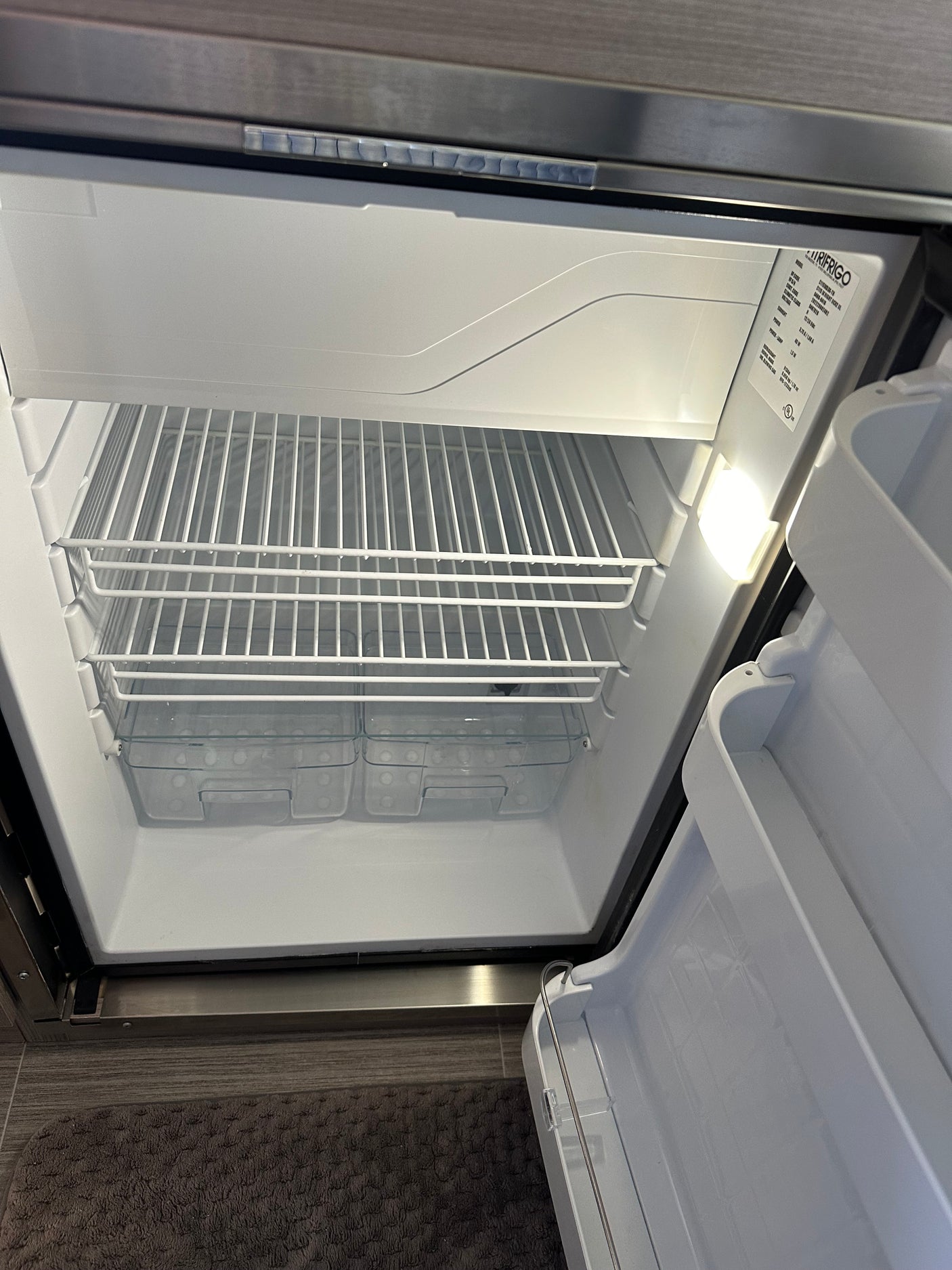 The clean, empty refrigerator interior of an rv rental, featuring wire shelves and clear bottom bins, ready for use.