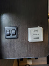 Essential RV rental features: a Dometic thermostat and dual rocker switches on a wood-grain panel for climate and lighting control.