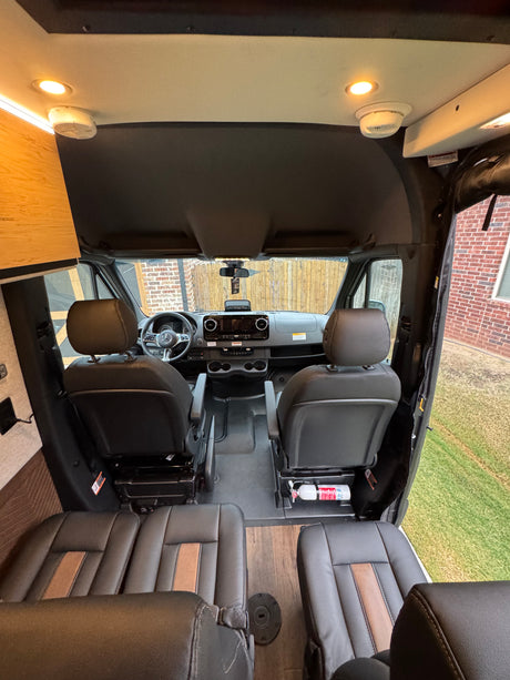 RV rental interior: View from back towards the front cabin, showing a Mercedes dashboard, seating, fire extinguisher, and smoke detector.