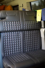 Quilted black seats in a modern RV rental camper van interior, offering comfort for your next adventure.