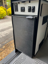 This rv rental features a Nova Kool fridge, GFCI outlet, and awning controls neatly integrated into the camper's design.