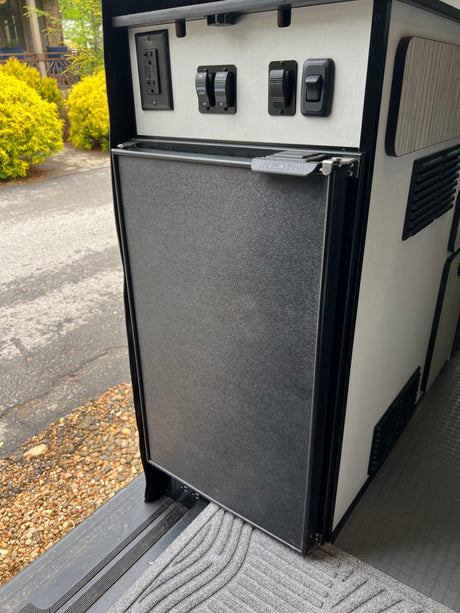 This rv rental features a Nova Kool fridge, GFCI outlet, and awning controls neatly integrated into the camper's design.