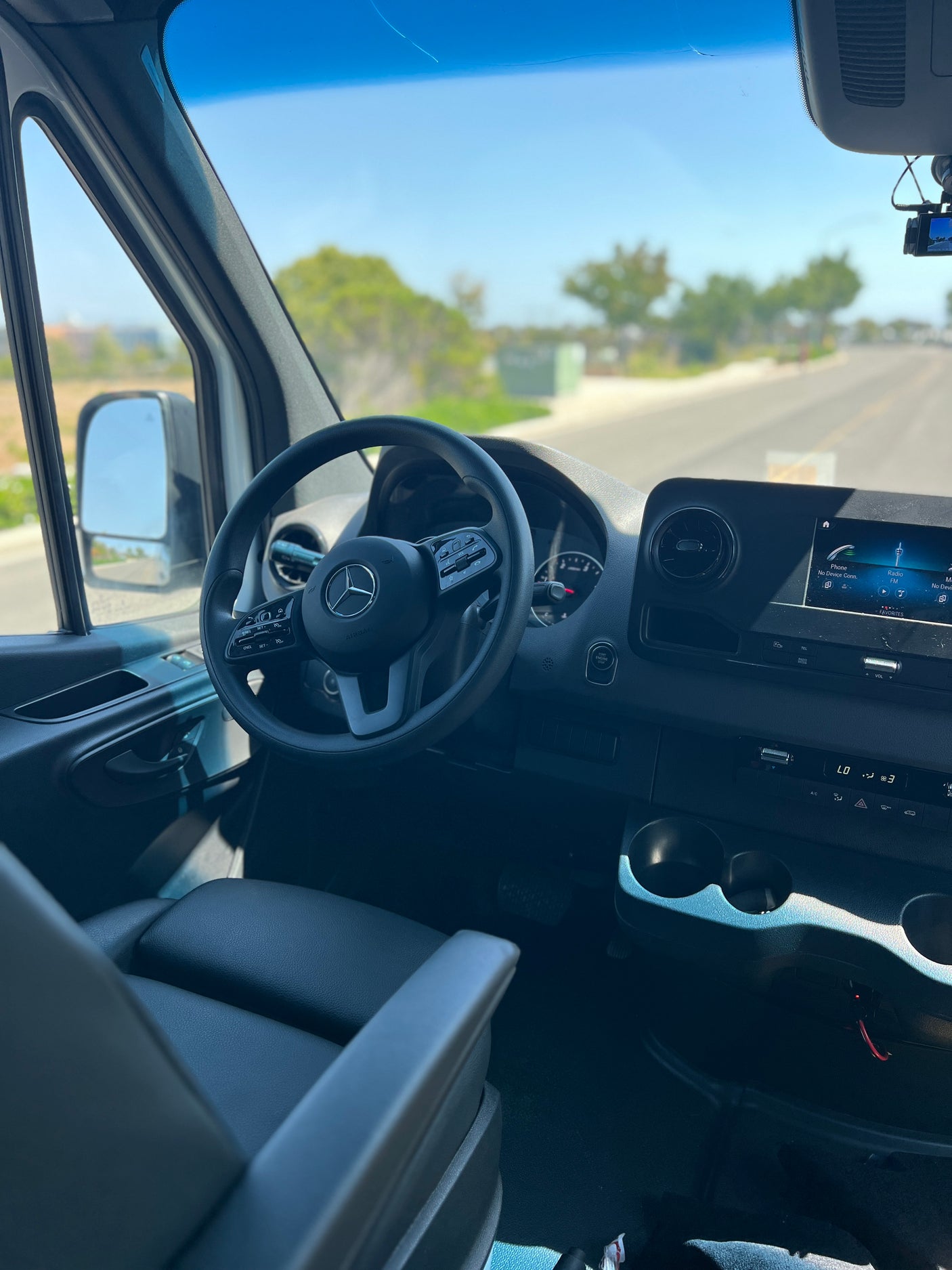 Inside an RV rental: a modern Mercedes-Benz van dashboard with steering wheel and infotainment screen, ready for the road.