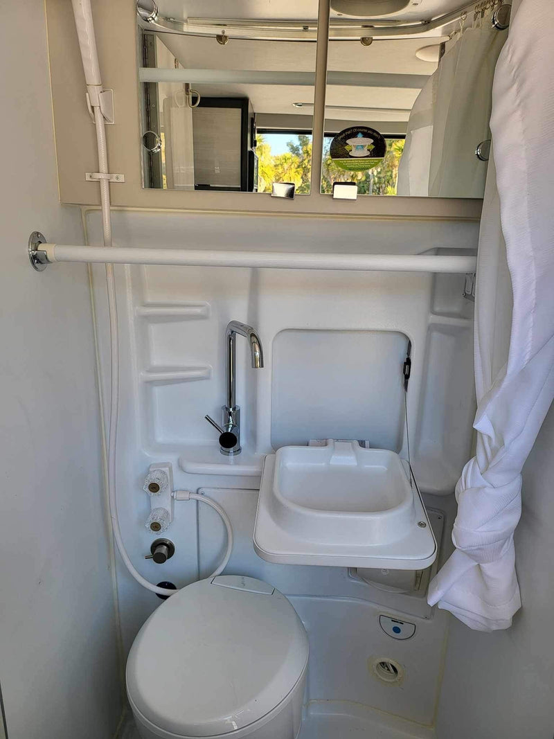 Compact wet bath in an RV rental, featuring a toilet, sink, and shower. Ideal for travel convenience. — photo 10