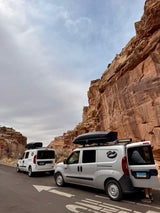 Two compact RV rental camper vans parked at impressive cliffs. Ideal for scenic road trips and outdoor adventures.
