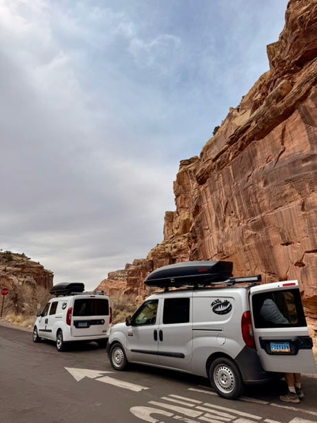 Two compact RV rental camper vans parked at impressive cliffs. Ideal for scenic road trips and outdoor adventures.