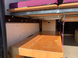 Inside an RV rental: a flexible bunk bed and seating area with custom wooden construction for comfort & storage.