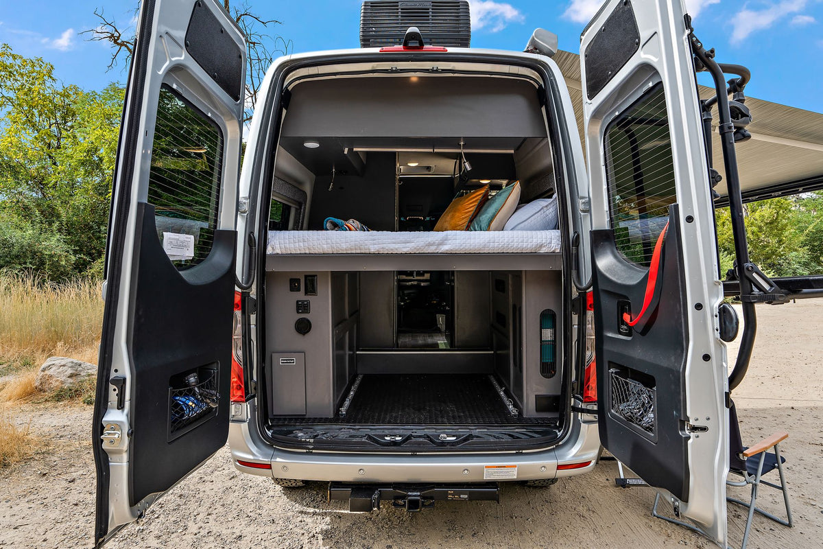  parked on dirt road. Perfect RV rental for adventures.|Cozy RV rental interior: a comfy bed with colorful blanket & pillows — photo 9