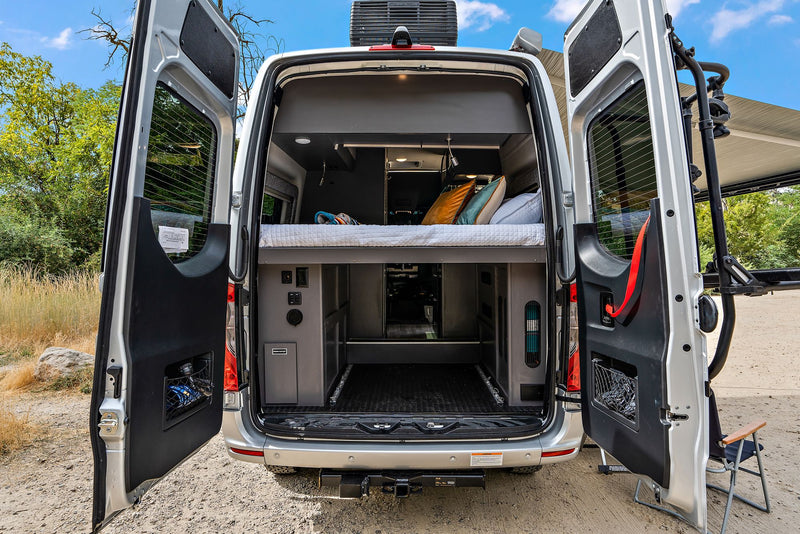 parked on dirt road. Perfect RV rental for adventures.|Cozy RV rental interior: a comfy bed with colorful blanket & pillows — photo 9
