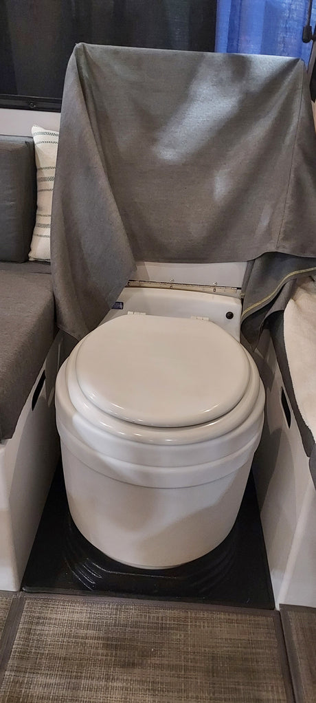 This RV rental features a compact toilet with a grey privacy curtain, located next to seating. Ideal for camper living.