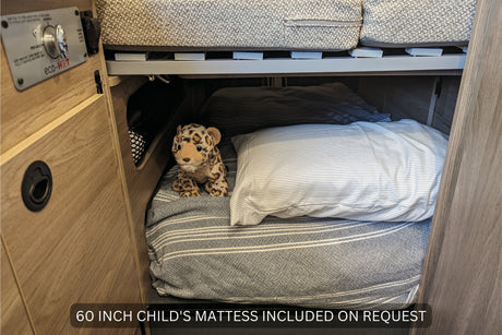 Inside an RV rental: a cozy lower bunk bed with a 60-inch child's mattress, pillow, and a stuffed leopard. Eco-Hot controls visible.