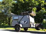 A rugged Taxa Tiger Moth off-road camping rv rental trailer with a rooftop tent, ready for adventure.