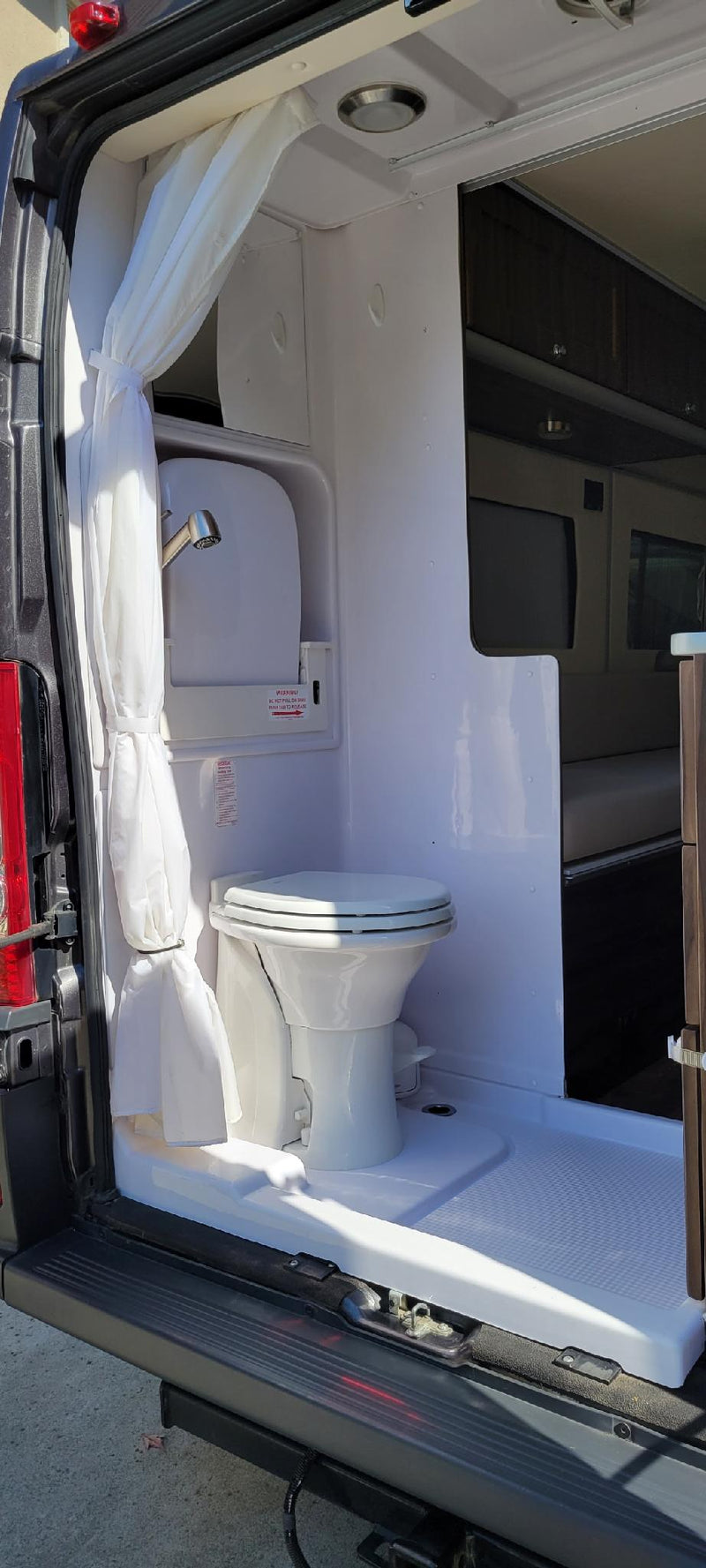 Inside an RV rental: a practical wet bath with toilet, pull-out shower faucet, and floor pan. — photo 6