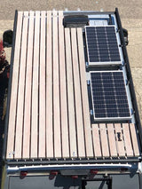 Rooftop view of an rv rental van featuring two solar panels and an expansive slatted wood deck. Ideal for extra cargo or outdoor living.