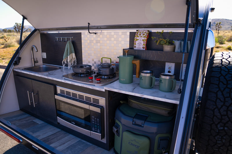  under dark wood cabinets & AC units.|Relaxing RV rental interior: a comfy bed with decorative sun pillows — photo 3