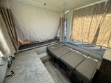 Inside an RV rental pop-up camper, featuring a bed, bench seating, and counter area. Perfect for camping adventures.