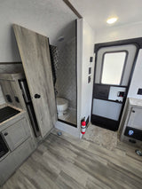 This rv rental showcases a functional interior with a kitchen, bathroom featuring a shower and toilet, and an emergency exit door.