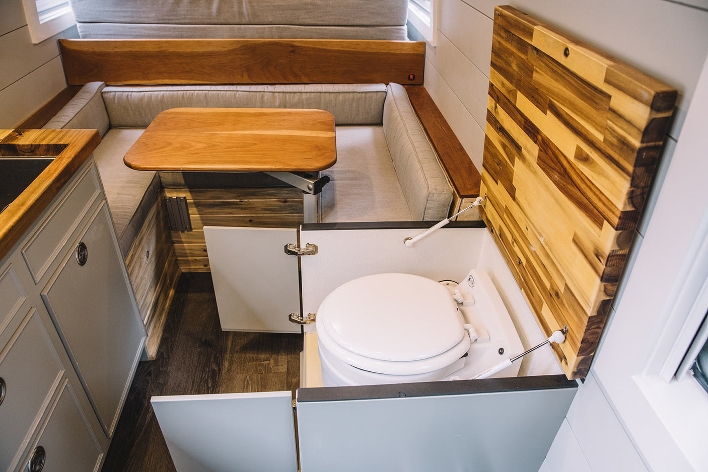 RV rental: Compact interior with U-shaped dinette, kitchen, and a cleverly concealed toilet under a wooden lift-top.