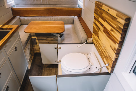 RV rental: Compact interior with U-shaped dinette, kitchen, and a cleverly concealed toilet under a wooden lift-top.