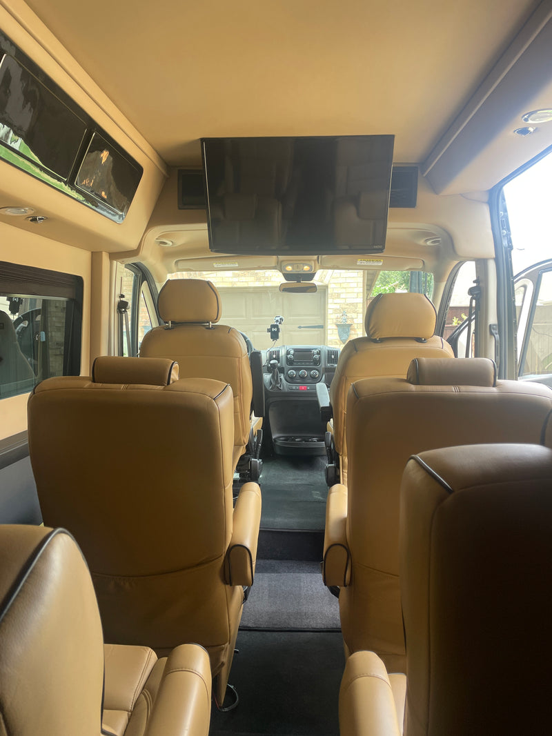 Luxury RV rental interior with tan leather captain's chairs and TV, perfect for comfortable travel. — photo 3