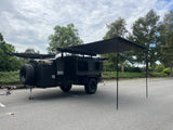 Dark Hiker Trailer RV rental, an off-road camper with extended awnings for shade, parked in a lot, ready for adventure.