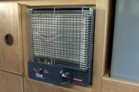 Olympian Wave 3 gas heater mounted in an RV rental interior, offering cozy warmth for camping.