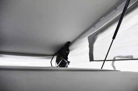 RV rental pop-top interior showing raised roof, black lift mechanism, and light canvas walls. Offers comfortable headroom.