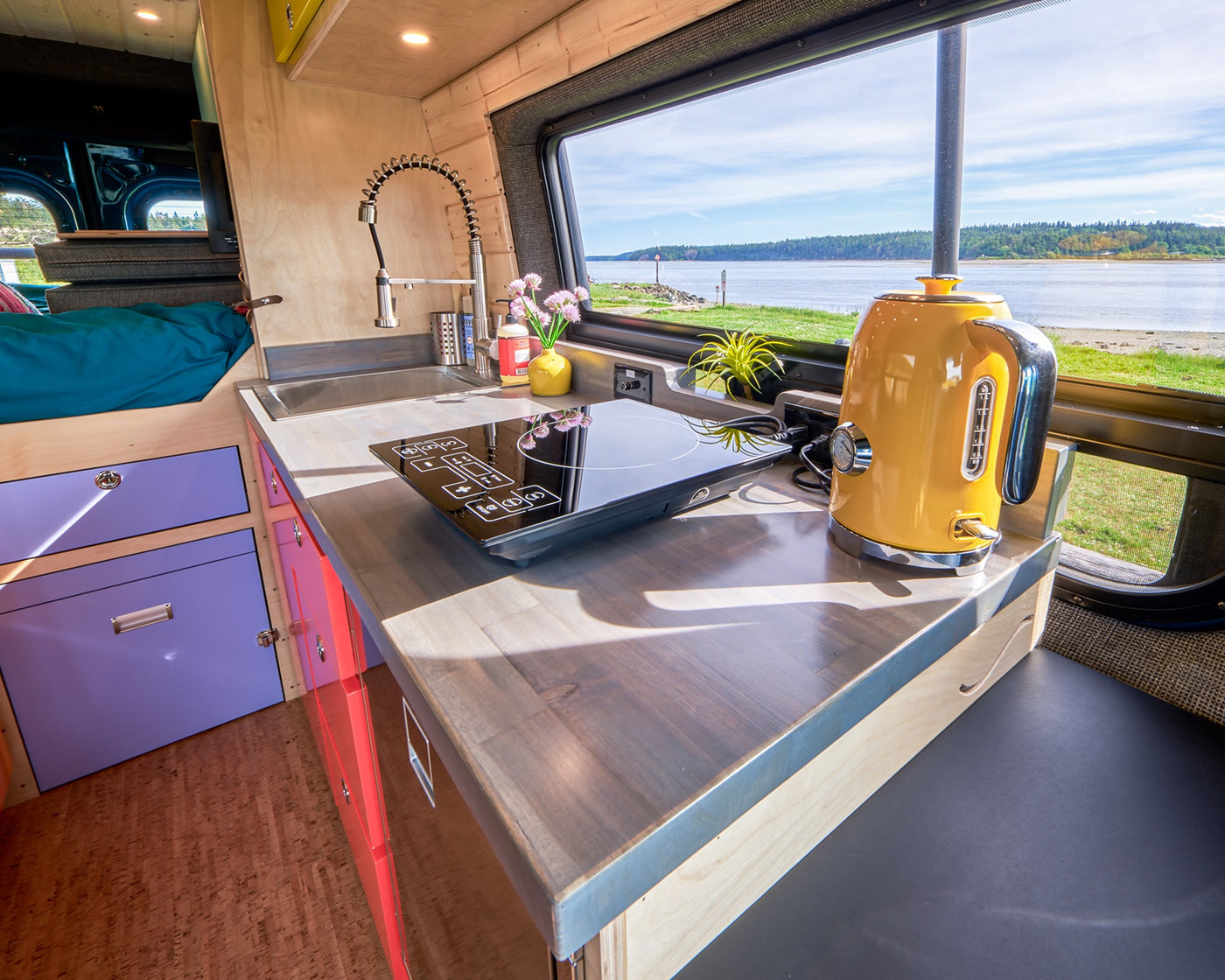 RV rental kitchen with sink, induction cooktop, and a yellow kettle, offering a scenic waterfront view. — photo 19