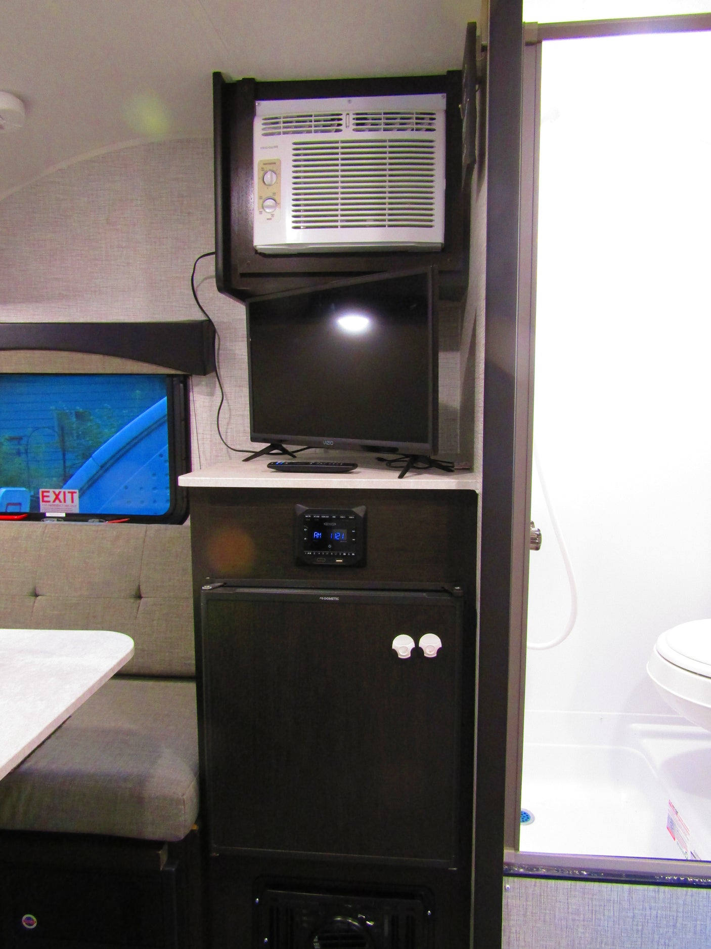 This RV rental interior features an AC, TV, fridge, dinette, and a peek into the compact bathroom, showing travel comfort.
