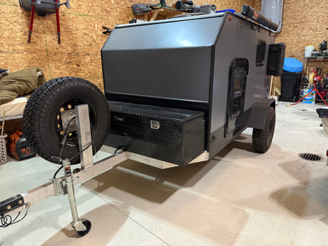 Explore the outdoors! This compact off-road camper trailer, perfect for your next rv rental adventure, boasts a spare tire and utility box.