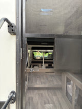 Inside an RV rental through a screen door: view of the interior with a "FISHHOOK" bunk, table, and flooring.