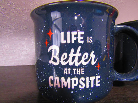 A navy blue speckled mug with red stars and white text "Life is Better at the Campsite," perfect for RV rental trips.