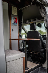 This RV rental features a cozy dining area with a table, padded bench, and unique wall decor, including Johnny Cash.