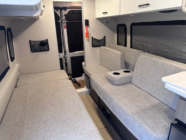 This RV rental offers a versatile interior with light gray convertible beds, sofa seating, and overhead storage.