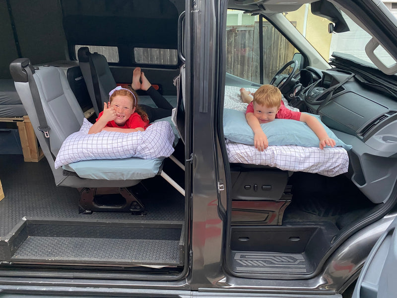 Happy kids relax on beds in an RV rental camper van. Great for family road trips & adventures! — photo 30