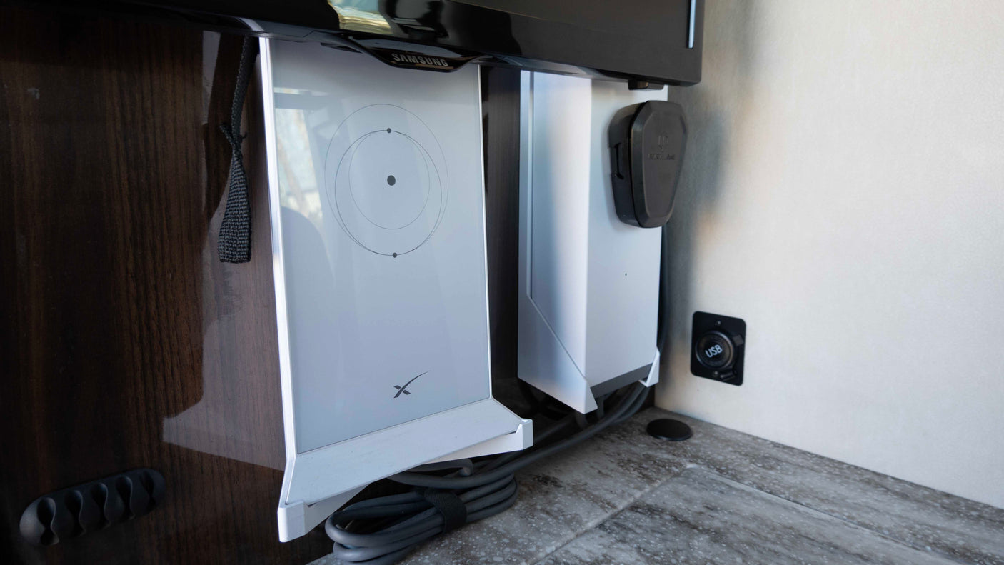 Starlink internet router and USB port provide modern connectivity in this RV rental, with cables neatly managed below a Samsung display.