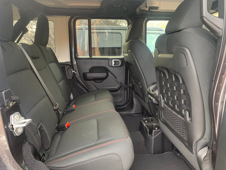 Inside a roomy RV rental: comfortable black rear seats with red stitching, secure seatbelts, convenient cup holders, and storage pockets.