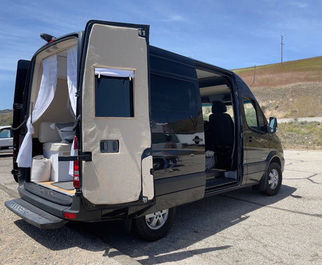 Black Sprinter van converted to an RV, doors open to reveal its cozy interior and a dog. Perfect for an rv rental adventure.