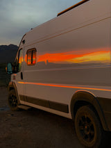 Stunning sunset reflecting vibrantly off a white RV rental, parked in a serene mountain desert.