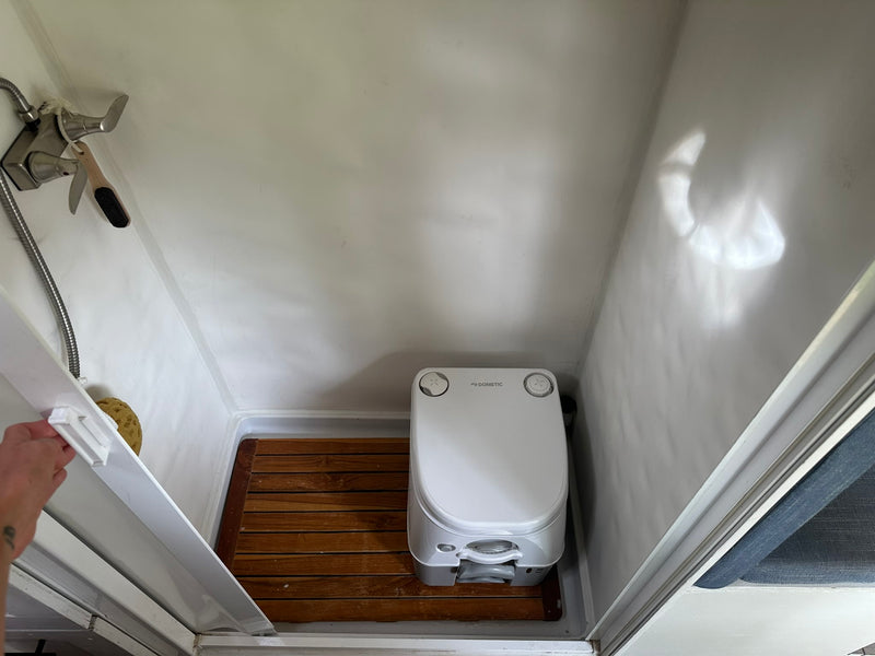 Inside an **rv rental**: a compact wet bath with a Dometic portable toilet, shower, and wooden floor mat. — photo 8