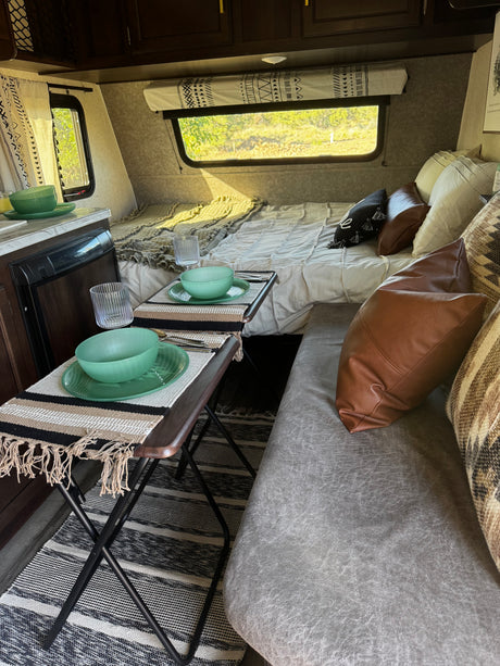 Cozy rv rental interior: A full bed, twin dining tables with settings, and a comfortable sofa are visible.