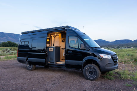 Explore the outdoors in this black custom Sprinter RV rental, featuring an open interior with kitchen and shower.