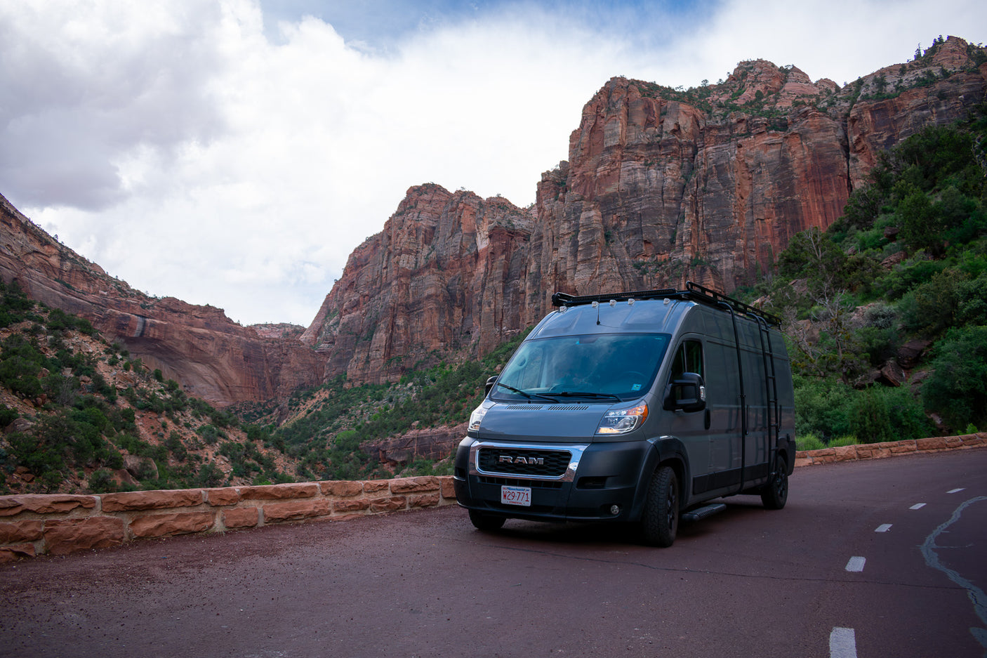 Gray RAM ProMaster rv rental van parked on a winding road with dramatic red rock canyons in the background.