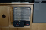 An RV rental amenity: a compact Wave catalytic heater, integrated into the wooden interior, for cozy travel warmth.