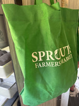 Green Sprouts Farmers Market reusable bag hangs in an RV rental, next to wire storage baskets.