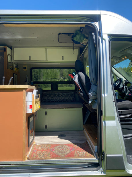 Step inside this cozy RV rental! Features a compact kitchen, bench seating, and scenic views for your next van life adventure.