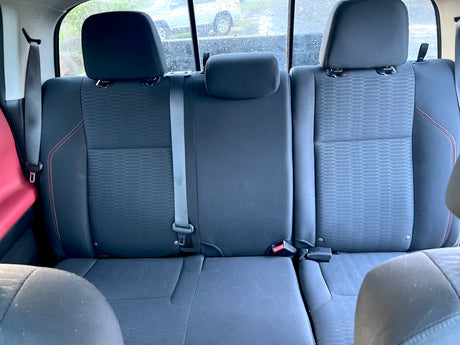 View of the dark fabric rear seats inside an RV rental, featuring three headrests, seatbelts, and a rainy window.