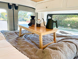 Morning coffee in your RV rental, served on a cozy bed with a wooden tray holding a pour-over kit and kettle.