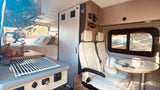 Spacious RV rental interior with bed, kitchen, swivel seats, and dining table, ready for your next adventure.
