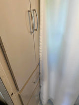 Compact storage in an RV rental: light cabinet with silver handles, drawers below, next to a white curtain, typical for a small interior.